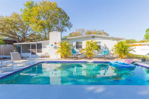 a view of a white house next to a yard with potted plants