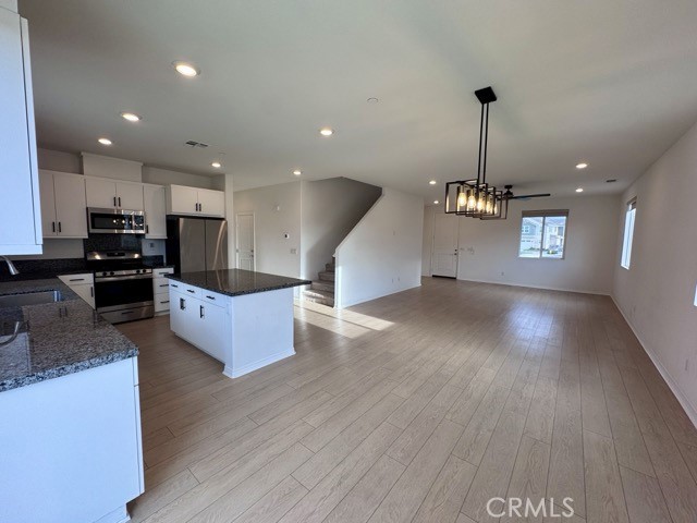 30115 Adrift Lane Menifee, CA 92584 - Photo 10 of 60 a open kitchen with stainless steel appliances kitchen island granite countertop a stove top oven a sink with wooden floors