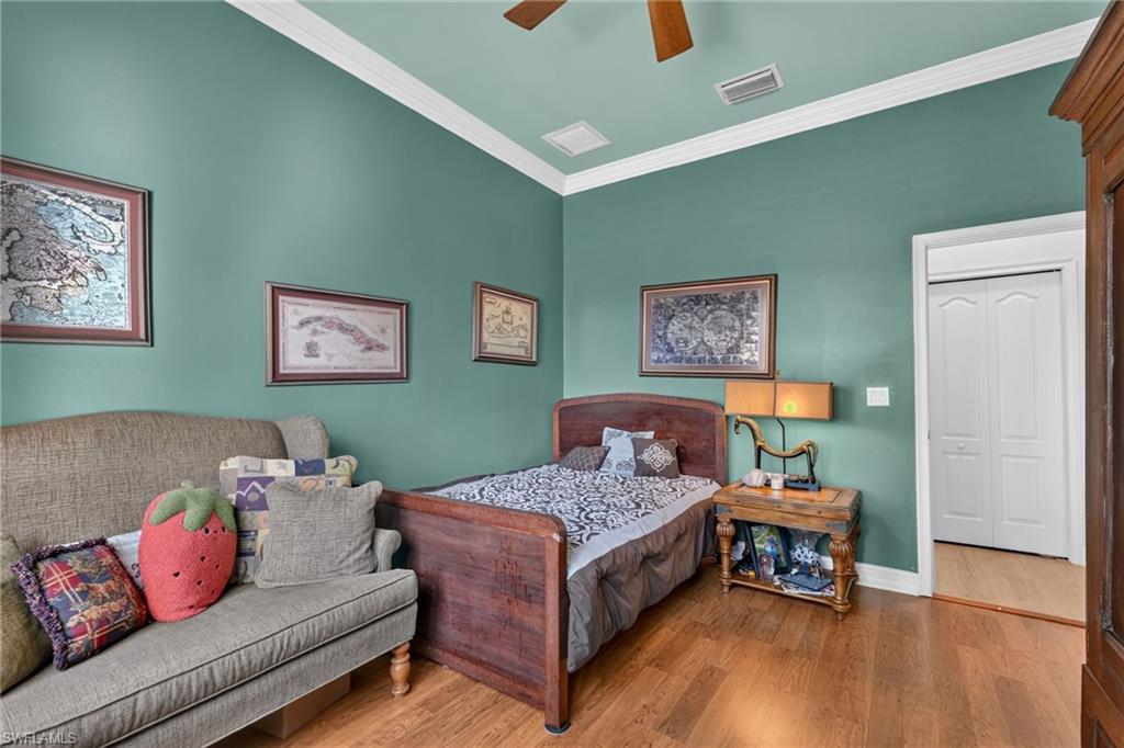 9970 Rookery Circle Estero, FL 33928 - Photo 22 of 50 Wood-finish flooring, crown molding, ceiling fan, and white bifold doors