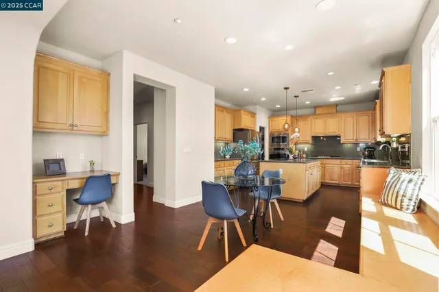 a living room with couches a coffee table and kitchen view with wooden floor