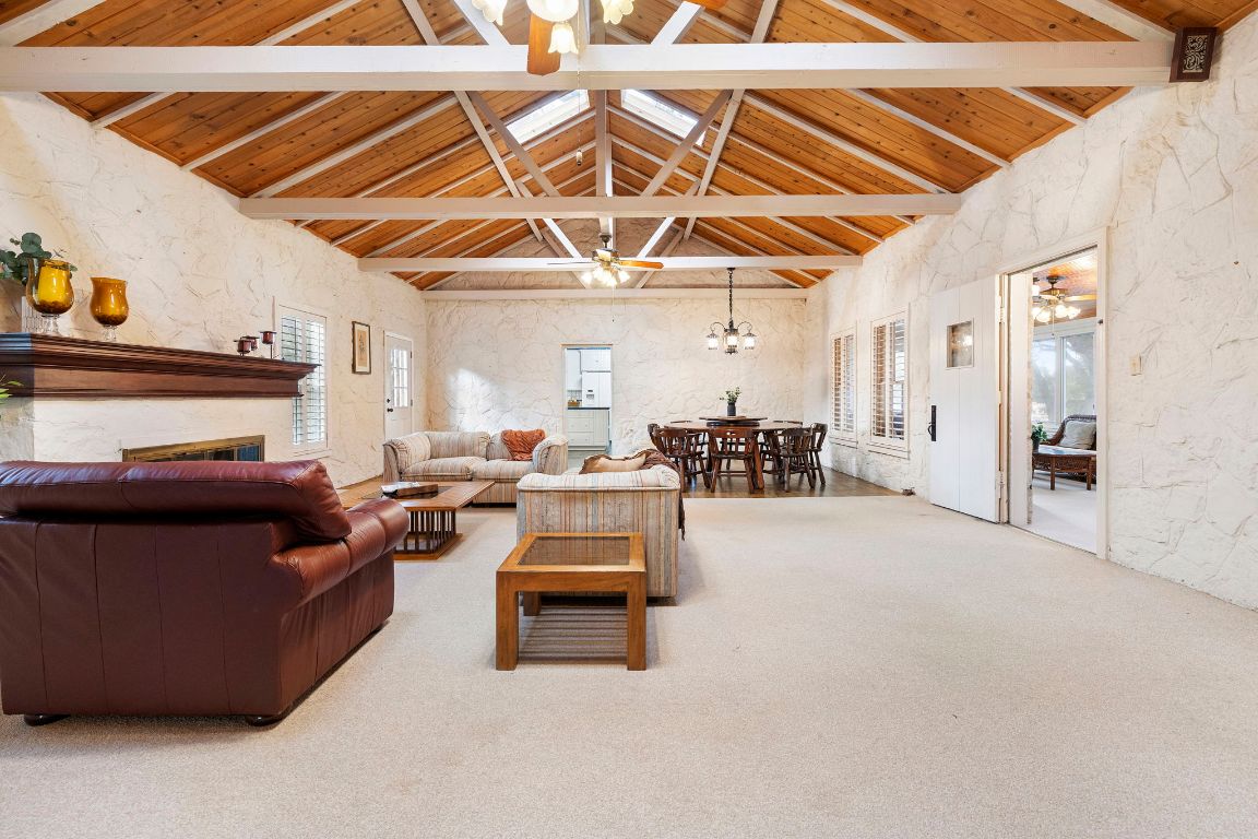 315 Flying R Ranch Road Spring Branch, TX 78070 - Photo 5 of 39 Carpeted living room with healthy amount of natural light, a wooden ceiling with exposed beams, a textured wall, ceiling fan, and a chandelier