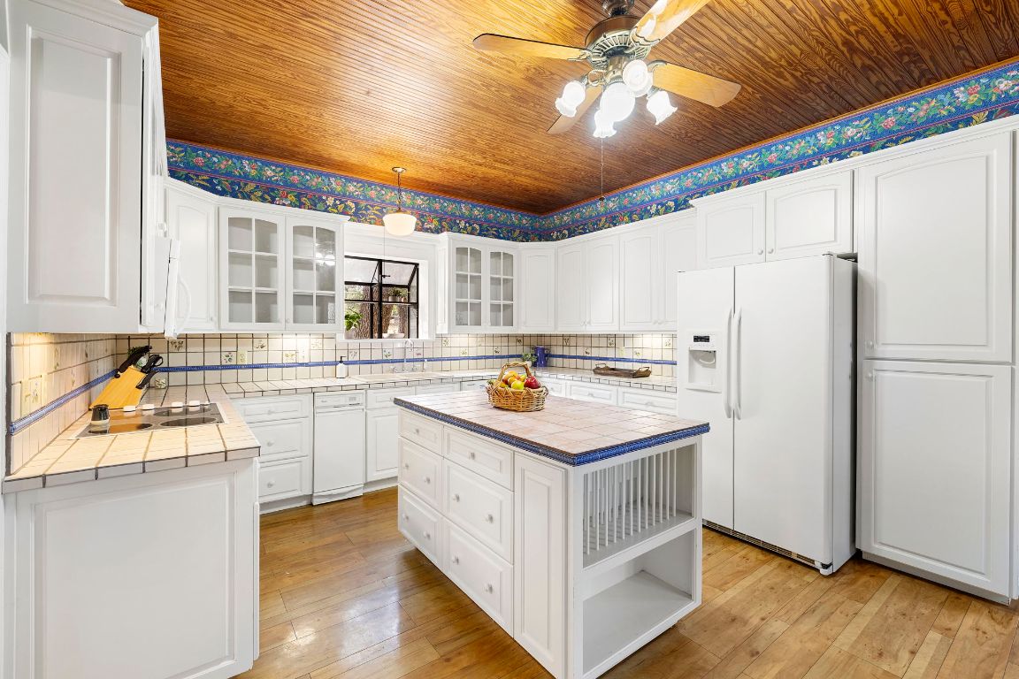 315 Flying R Ranch Road Spring Branch, TX 78070 - Photo 9 of 39 Kitchen with tile countertops, white fridge with ice dispenser, white cabinetry, a kitchen island, and open shelves