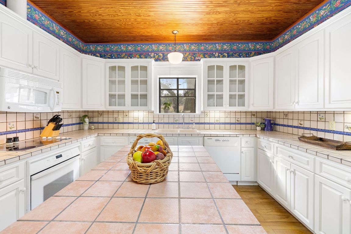 315 Flying R Ranch Road Spring Branch, TX 78070 - Photo 10 of 39 Kitchen featuring white cabinetry, tile countertops, white appliances, wood ceiling, and glass insert cabinets