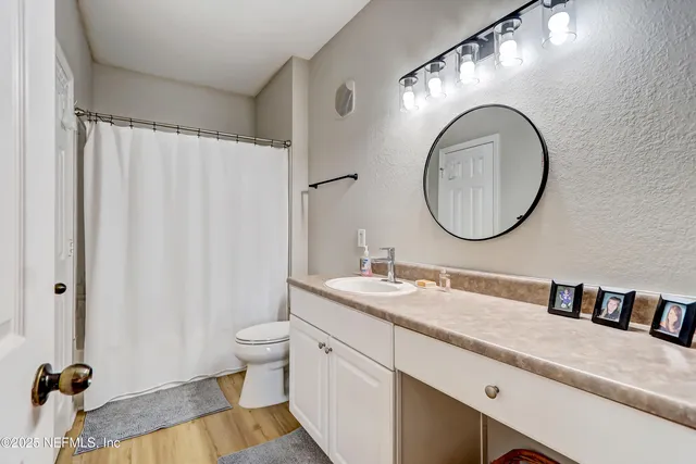 a bathroom with a granite countertop toilet a sink and a mirror