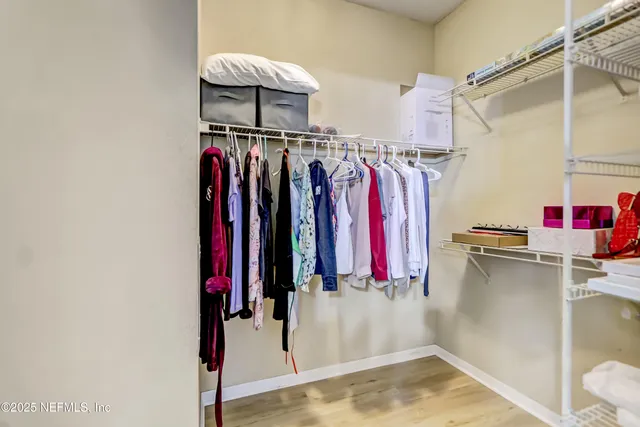 a view of walk in closet with clothes and shoes