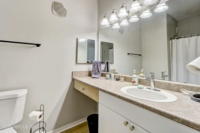 a bathroom with a granite countertop sink a toilet and a mirror