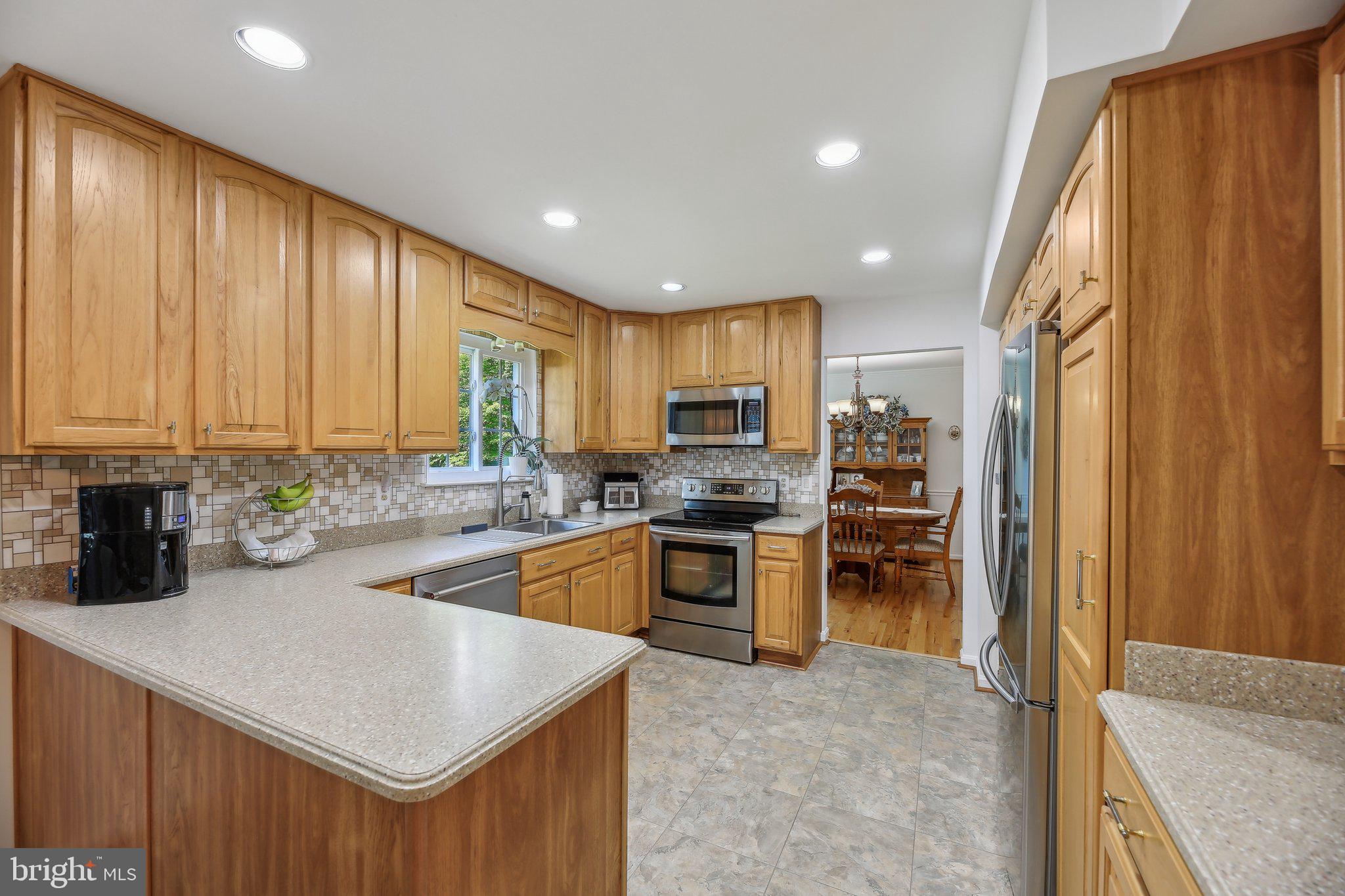 9202 Stone Spring Lane Pasadena, MD 21122 - Photo 14 of 43 a kitchen with a sink a counter top space stainless steel appliances cabinets and a window