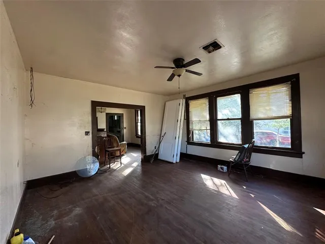 a view of an empty room with a window and wooden floor