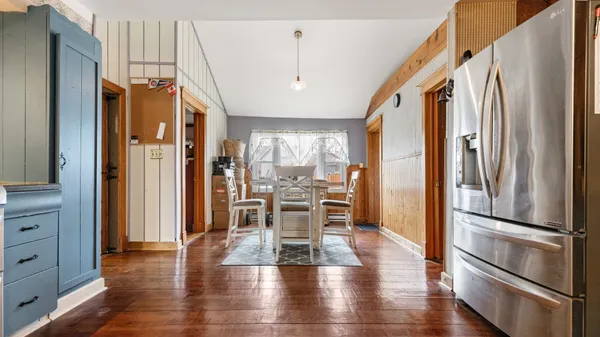 a dining room with wooden floor chandelier and glass door