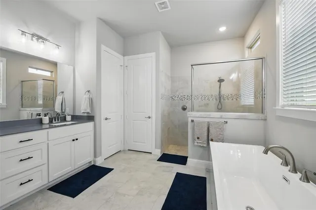 a bathroom with a sink double vanity granite tub shower and a mirror
