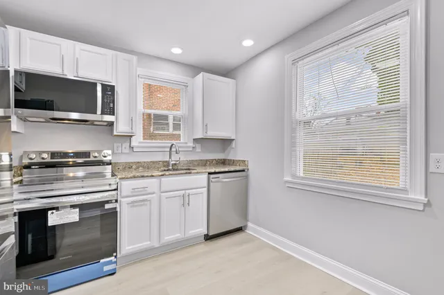a kitchen with granite countertop a stove top oven sink and cabinets