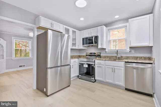 a kitchen with stainless steel appliances granite countertop a refrigerator a stove a sink and a microwave