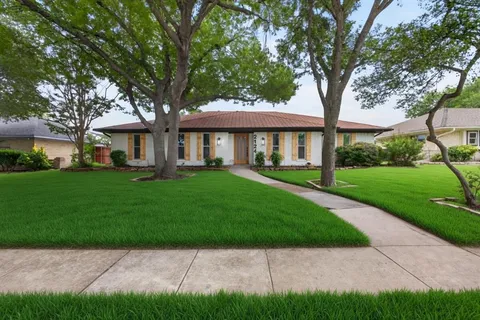 an aerial view of a house with a yard and large tree