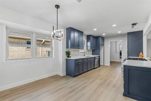 a kitchen with stainless steel appliances kitchen island granite countertop wood cabinets and a wooden floor