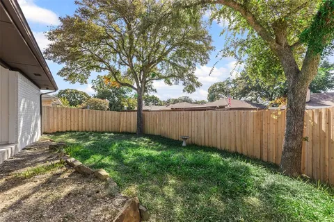 a view of a backyard with a trees and wooden fence