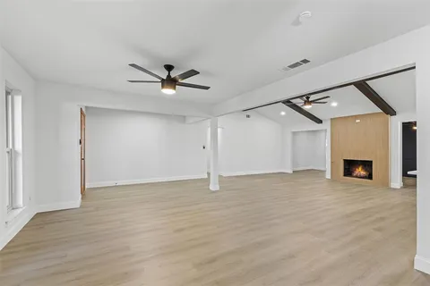 an empty room with fireplace and a ceiling fan