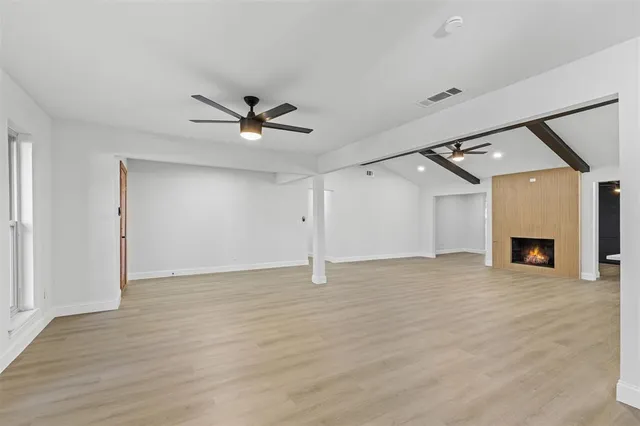 an empty room with fireplace and a ceiling fan