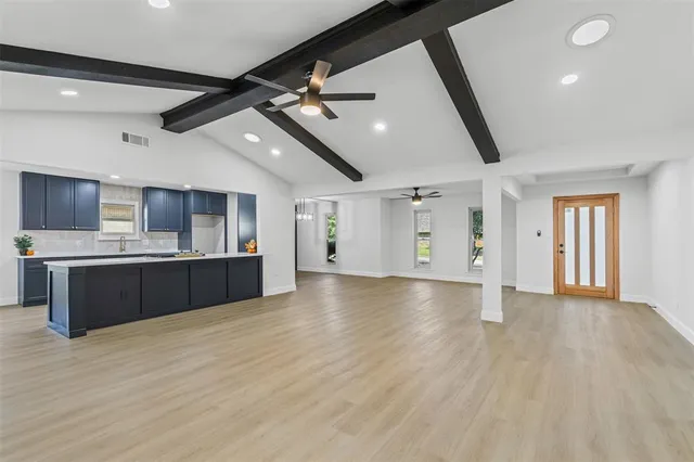 a view of a big room with wooden floor and windows