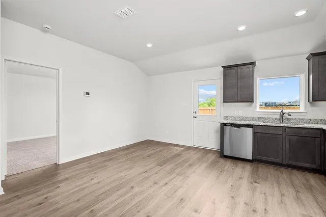 a kitchen with granite countertop a stove a sink and a refrigerator