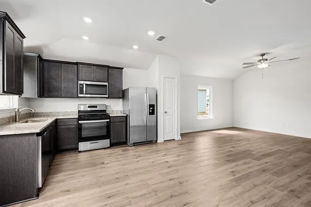 a kitchen with stainless steel appliances granite countertop a refrigerator stove top oven and sink