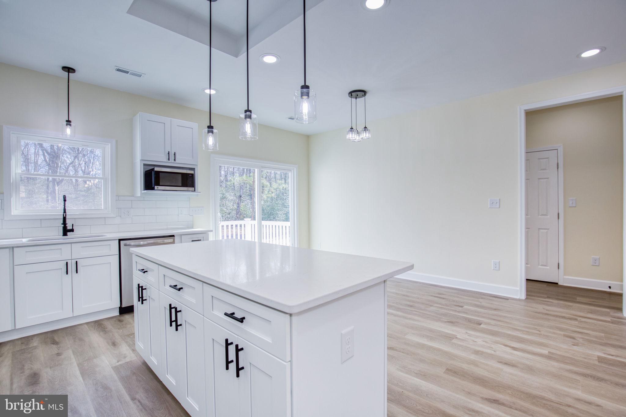 49 Poplar Lane Colonial Beach, VA 22443 - Photo 6 of 42 a kitchen with stainless steel appliances granite countertop a sink stove and white cabinets with wooden floor