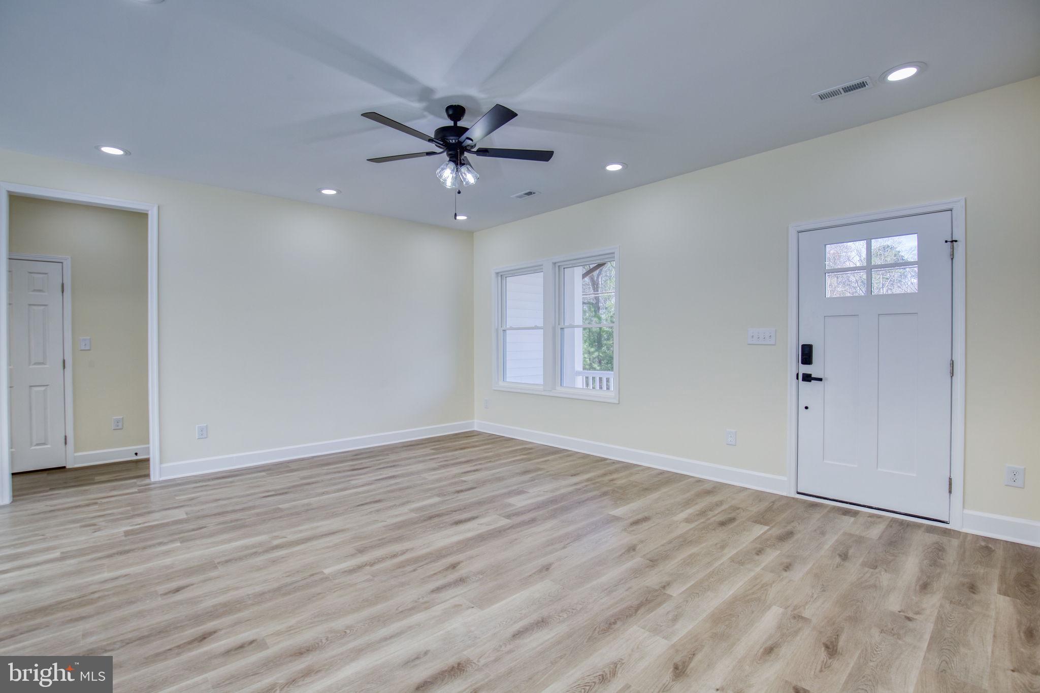 49 Poplar Lane Colonial Beach, VA 22443 - Photo 10 of 42 an empty room with wooden floor chandelier fan and windows