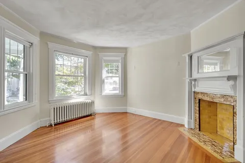wooden floor fireplace and windows in an empty room