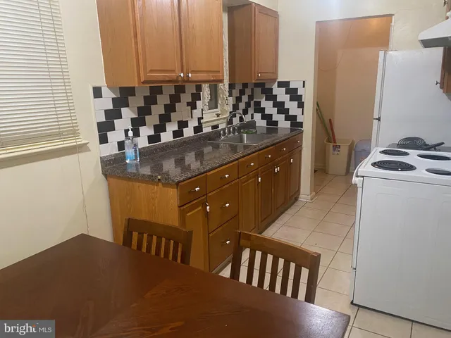 a kitchen with granite countertop a sink a stove and refrigerator