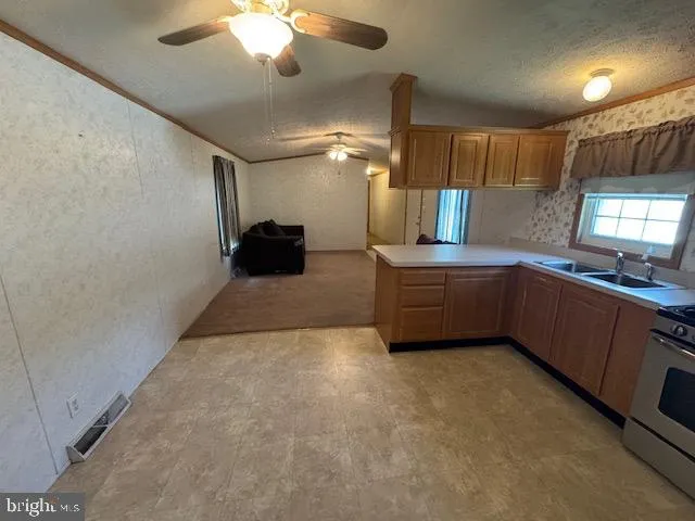 a large kitchen with a large counter top a sink stainless steel appliances and cabinets