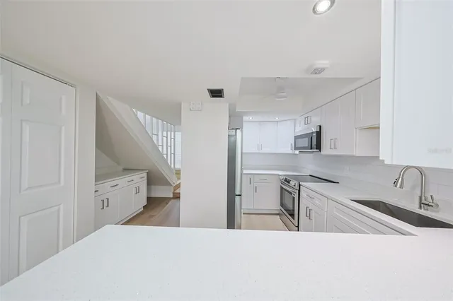 a kitchen with a sink dishwasher and white cabinets with wooden floor