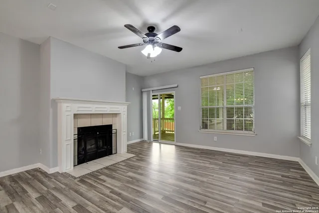 a view of an empty room with wooden floor fireplace and a window
