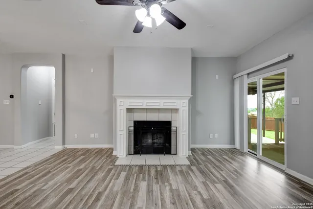 a view of an empty room with wooden floor fireplace and a window