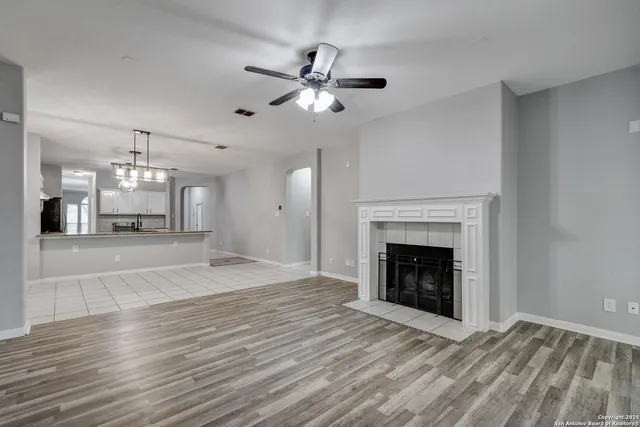 a view of an empty room with a fireplace and chandelier fan