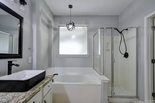 a bathroom with a granite countertop sink a mirror and shower