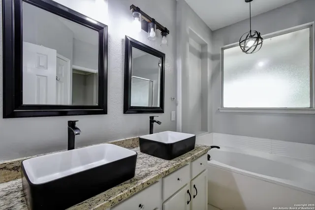 a bathroom with double vanity sinks and a mirror