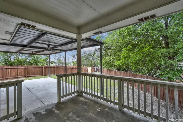 a view of a backyard with large trees and wooden fence