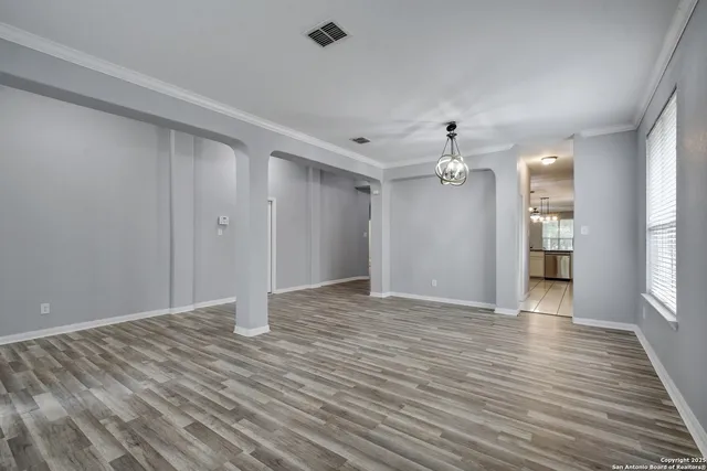 a view of an empty room with window and wooden floor