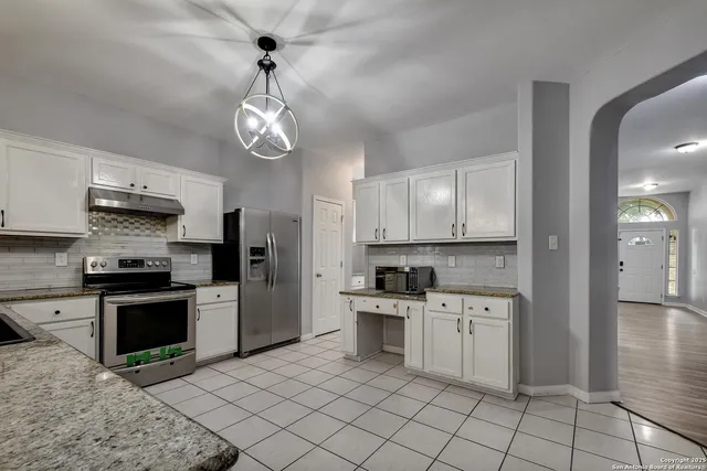 a kitchen with stainless steel appliances granite countertop a stove a sink and a refrigerator