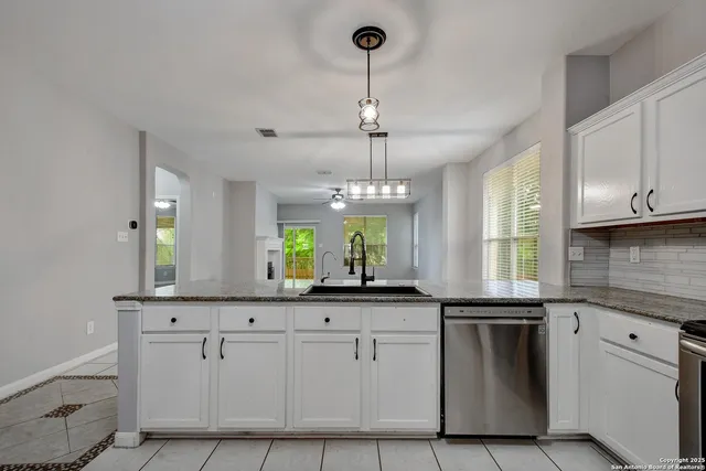 a kitchen with white cabinets and chandelier