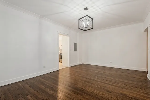 a view of an empty room with wooden floor and windows