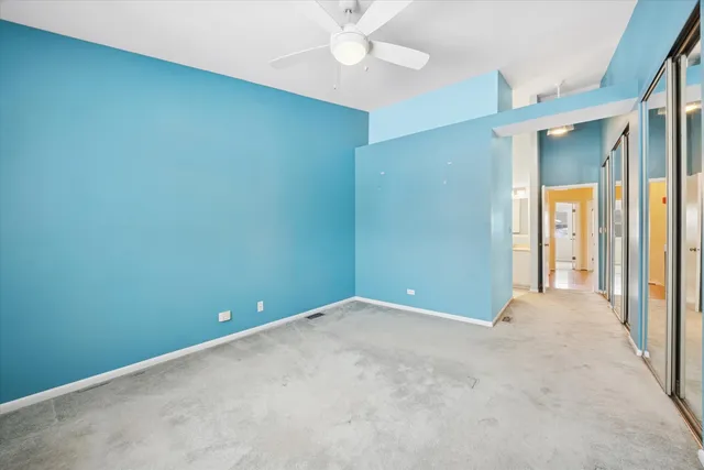 an empty room with a fan & a window