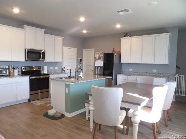 a kitchen with stainless steel appliances granite countertop a stove a sink a microwave a dining table and chairs