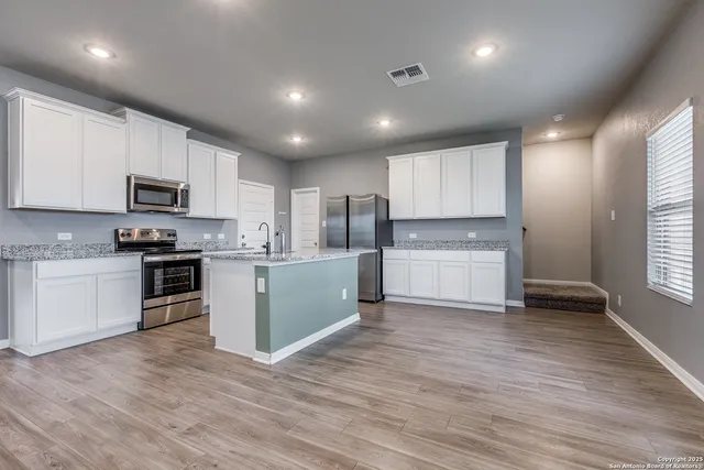 a kitchen with stainless steel appliances granite countertop a refrigerator oven a sink dishwasher and a stove with wooden floor