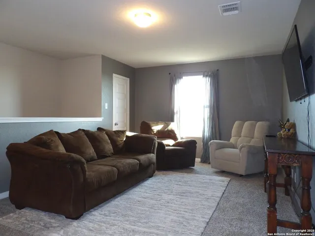 a living room with furniture a flat screen tv and a window