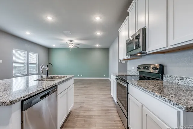 a kitchen with granite countertop stainless steel appliances a sink stove top oven and cabinets