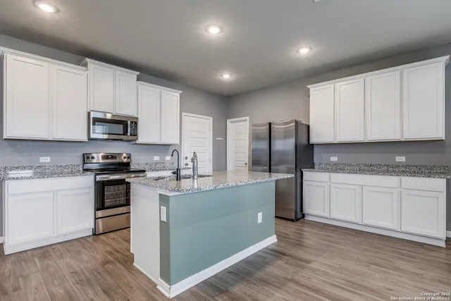 a kitchen with stainless steel appliances granite countertop a stove top oven a sink and dishwasher a refrigerator with wooden floor