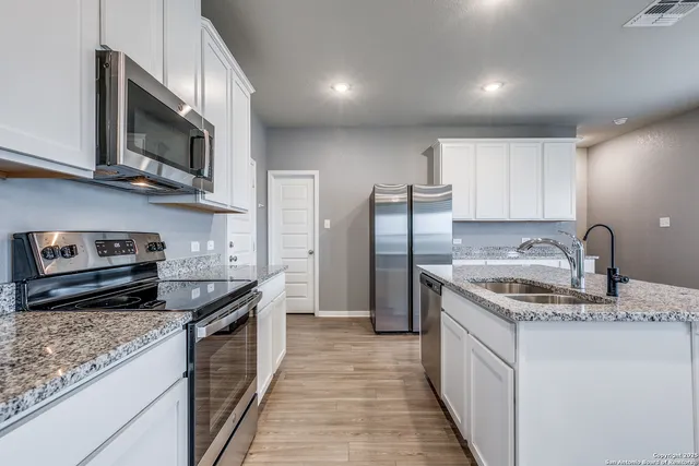 a kitchen with stainless steel appliances granite countertop a sink stove microwave and refrigerator