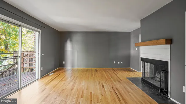 a view of empty room with wooden floor and fireplace