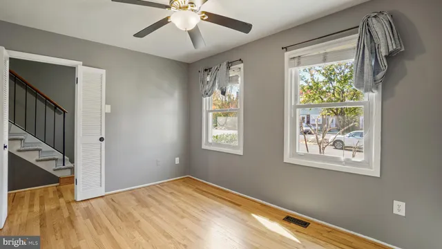 a view of empty room with wooden floor and fan