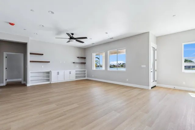 a view of an empty room with window and wooden floor